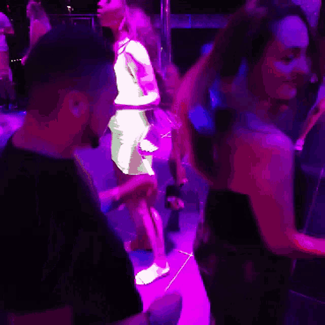 a man and a woman are dancing in a purple light
