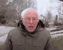 bernie sanders is wearing a jacket with a hood and glasses while standing in the snow .