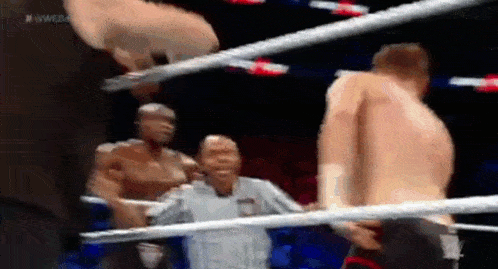 a referee is standing in the middle of a boxing ring while two men are fighting .