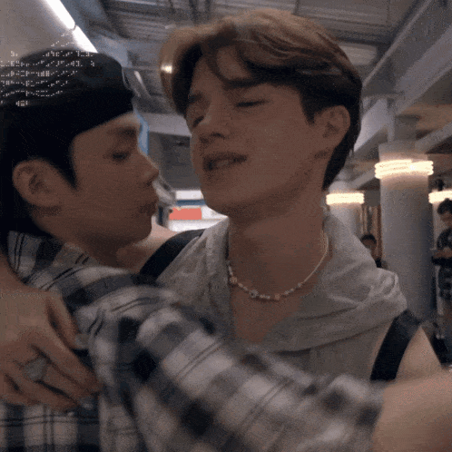 a man wearing a plaid shirt is hugging another man