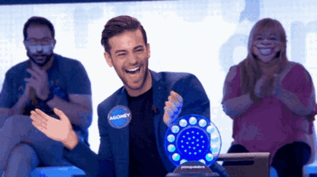 a man wearing a tag that says agoney is laughing
