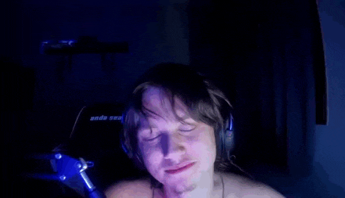 a man wearing headphones is sitting in front of a microphone with his eyes closed .