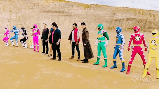a group of power rangers are standing in a line in the dirt .