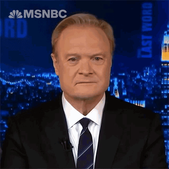 a man in a suit and tie stands in front of a msnbc logo