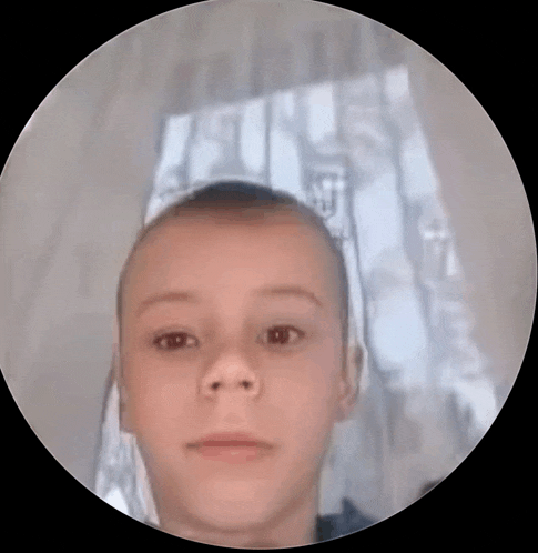 a young boy with a shaved head is looking at the camera in a circle