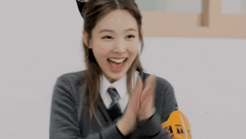 a girl in a school uniform is holding a pumpkin in her hands and smiling .