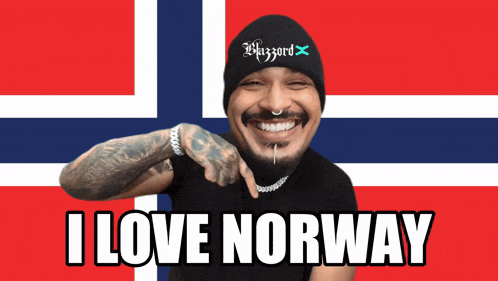a man wearing a beanie that says blizzard is pointing at the camera and says " i love norway "