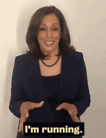 a woman in a suit and necklace is smiling and saying i 'm running