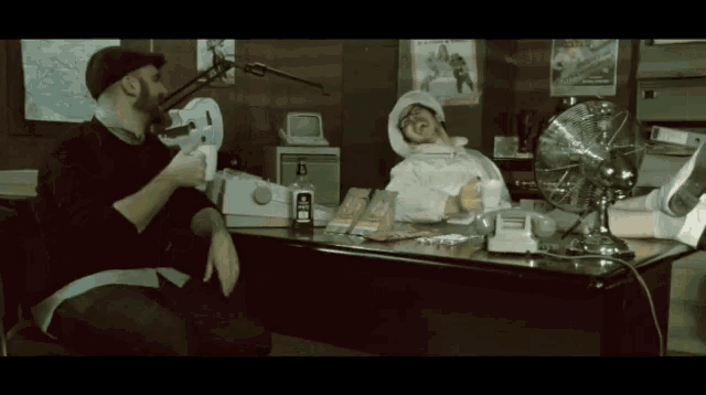 a man sits at a desk with a bottle of jack daniel 's on it