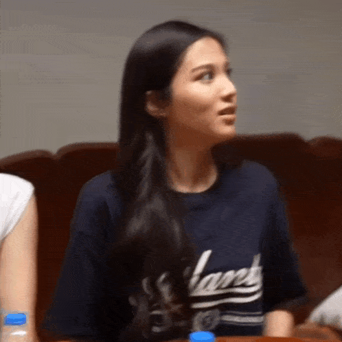 a woman wearing a t-shirt that says lanes is sitting on a couch