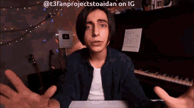 a young man is sitting in front of a piano with his hands out
