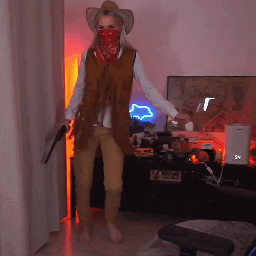 a woman in a cowboy costume is holding two guns and wearing a bandana around her face