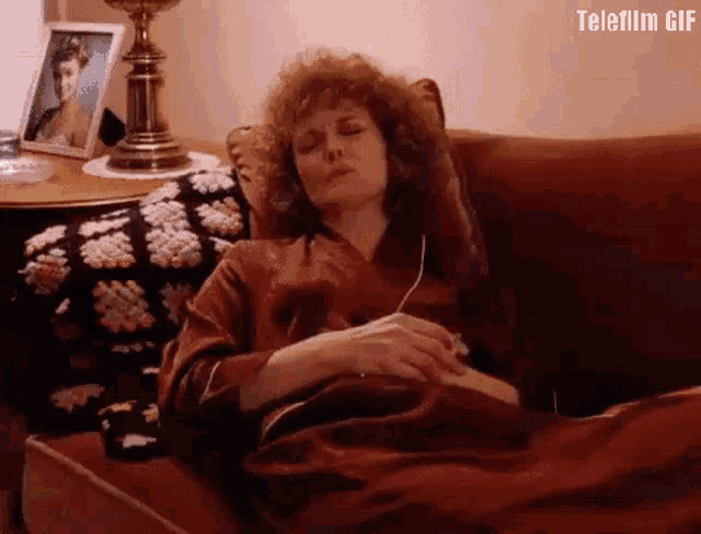 a woman is laying on a couch with her eyes closed while listening to music .