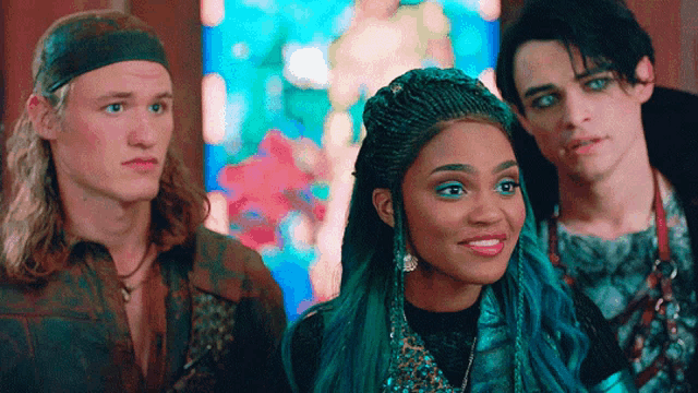 a girl with blue hair is smiling while standing next to two other people