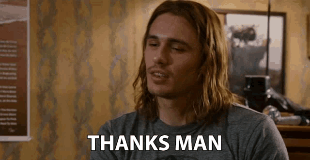 a man with long hair says thanks man in front of a wall