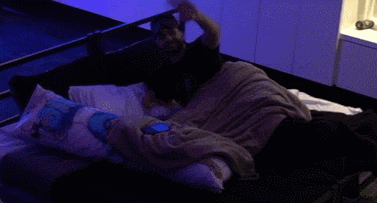 a person is laying on a bed with a blue light shining on their phone