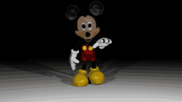 a mickey mouse toy is standing in the dark and looking at the camera