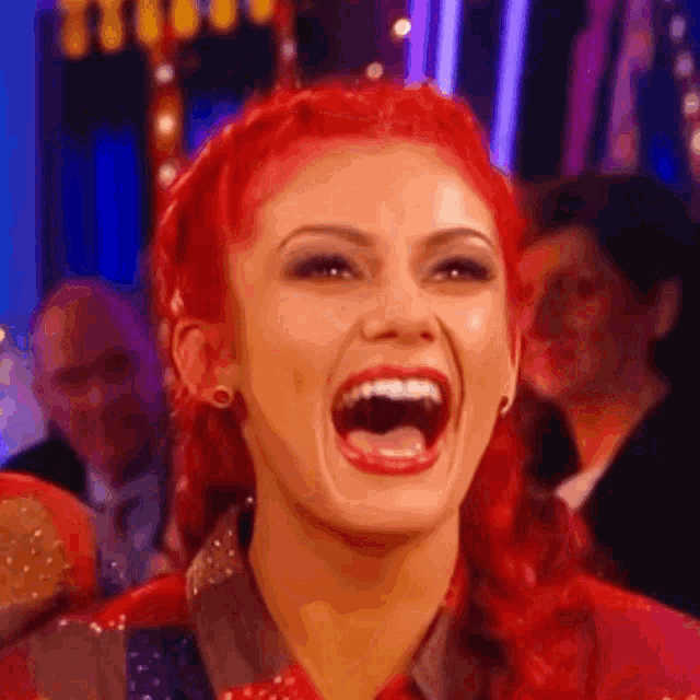 a close up of a woman with red hair laughing with her mouth open .