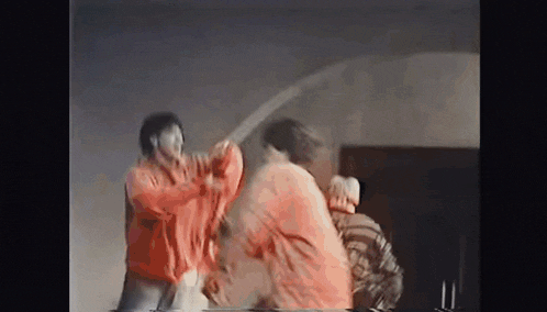 a group of people are standing in a room fighting each other with swords .