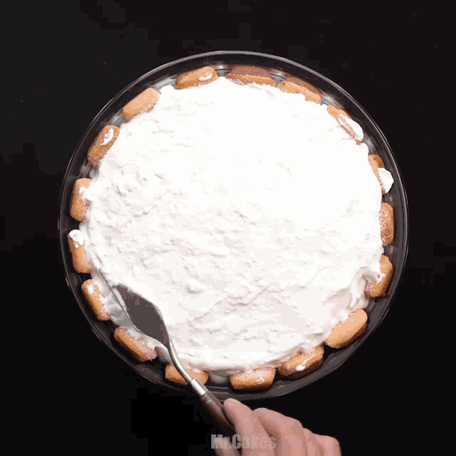 a person is spreading whipped cream on top of a cake that says mr.cakes
