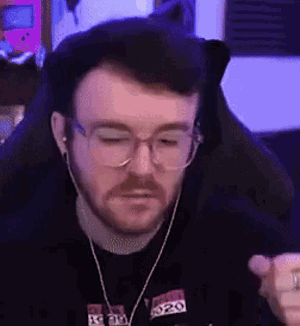 a man with a beard and glasses is wearing headphones and a black shirt .