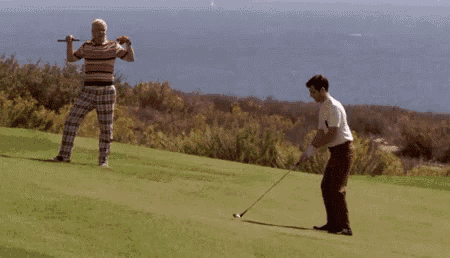 a man swinging a golf club at another man