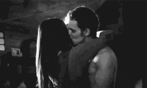 a man and a woman are kissing in a dark room .