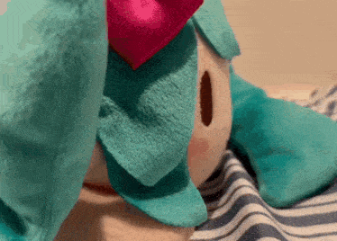 a stuffed animal with a pink bow on it 's head is laying on a bed .