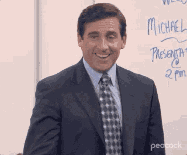 a man in a suit and tie is smiling in front of a white board that says michael .