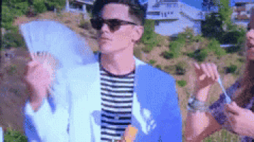 a man in a blue suit and sunglasses is standing next to a woman in a striped shirt