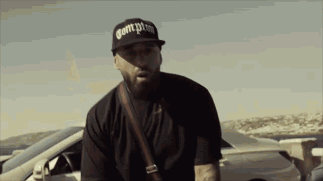 a man with a beard wearing a compton hat