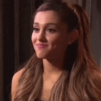 ariana grande is smiling and looking at the camera while wearing a black dress .