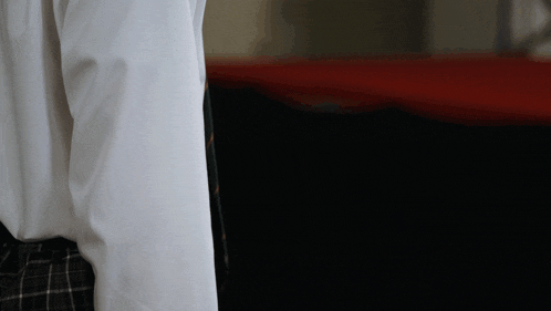a person wearing a white shirt and plaid skirt is standing in a dark room