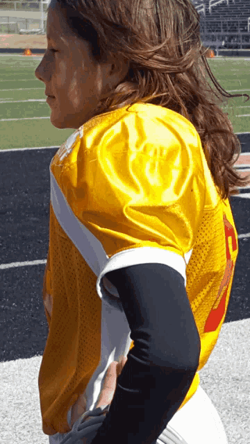 a young girl wearing a yellow jersey with the number 7 on the back