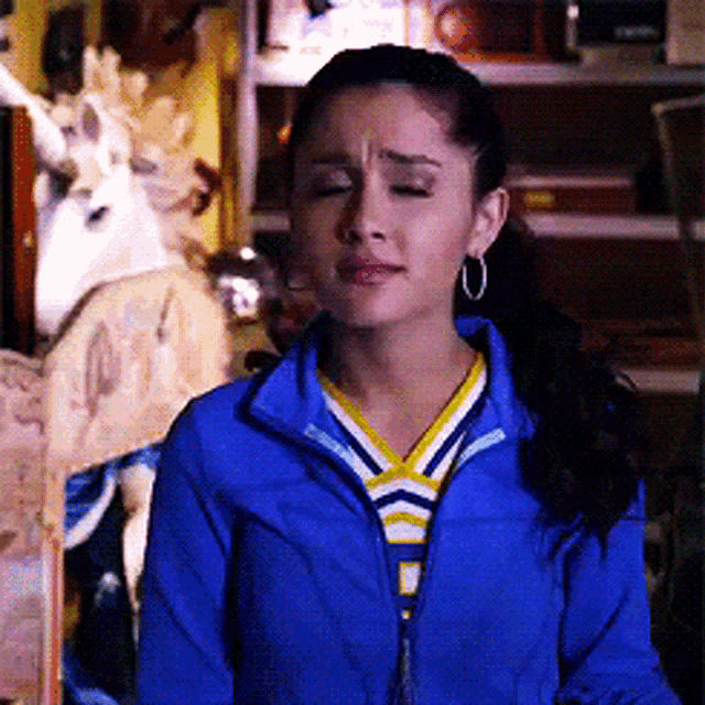 a woman wearing hoop earrings and a blue jacket is standing in front of a unicorn statue