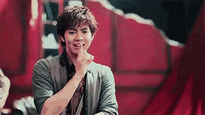 a young man is holding his finger to his lips and making a funny face .