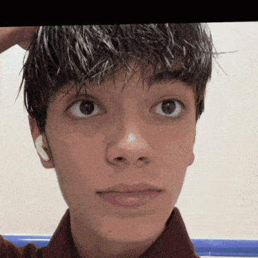 a close up of a young man 's face with a white ear bud in his ear