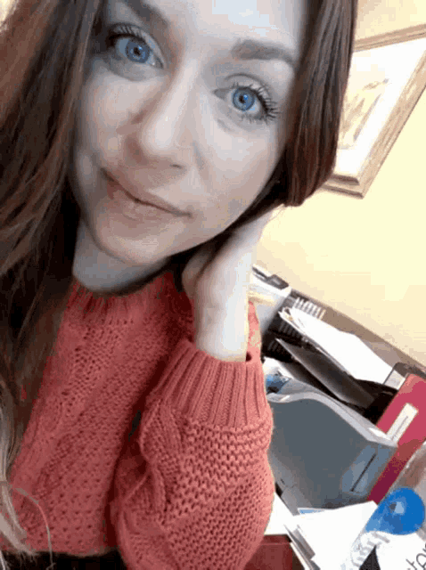 a woman wearing a red sweater has blue eyes and is smiling for the camera
