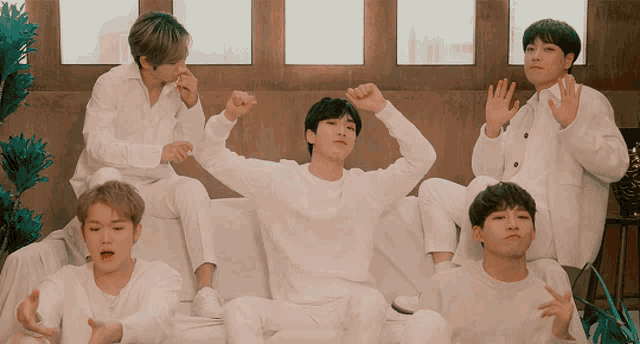 a group of young men sitting on a couch with their arms up