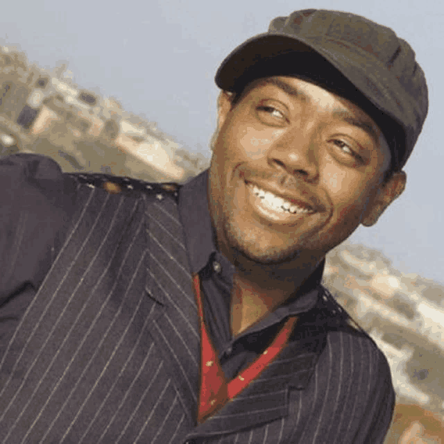 a man wearing a hat and a vest smiles for the camera