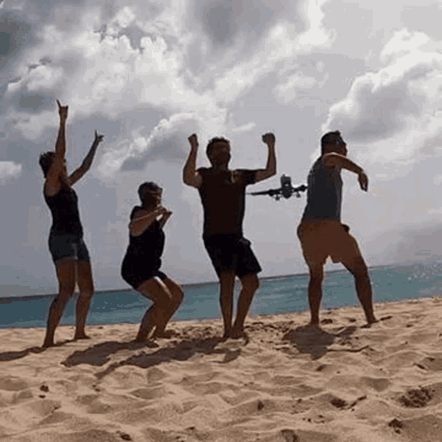 a group of people are dancing on a beach while a plane is flying in the background .