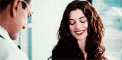 a woman is smiling while talking to a man in a white coat .