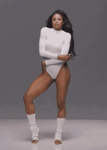 a woman in a white bodysuit and white leg warmers