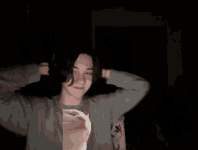 a person with their hands on their head wearing a grey sweatshirt