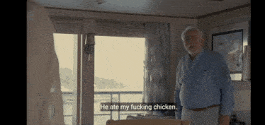 a man in a blue shirt is standing in a living room and talking about chicken .