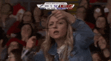 a woman wearing glasses is watching a game and the score is 1 to 1