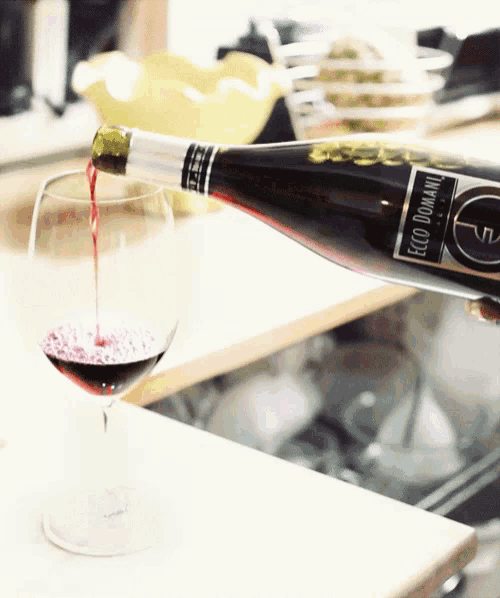 a bottle of ecco domaine wine is pouring into a glass