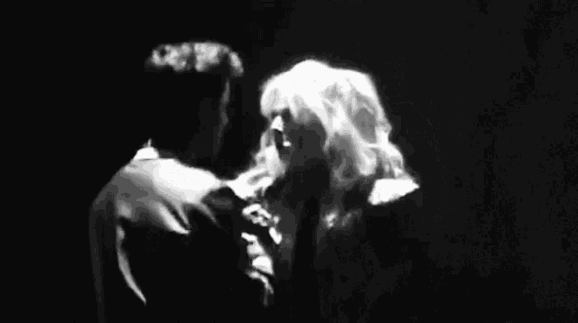 a black and white photo of a man and a woman dancing on a stage .
