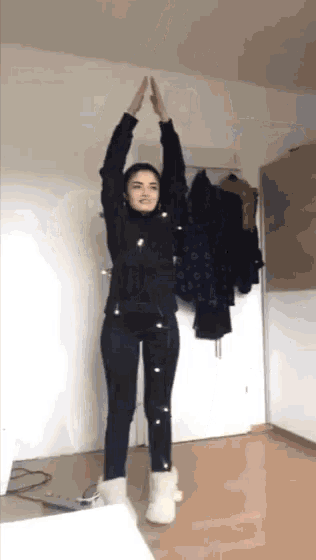 a woman is standing in a room with her arms up