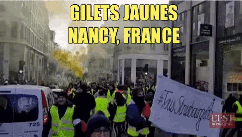 a group of people wearing yellow vests are marching down a street with the words gilets jaunes nancy france above them